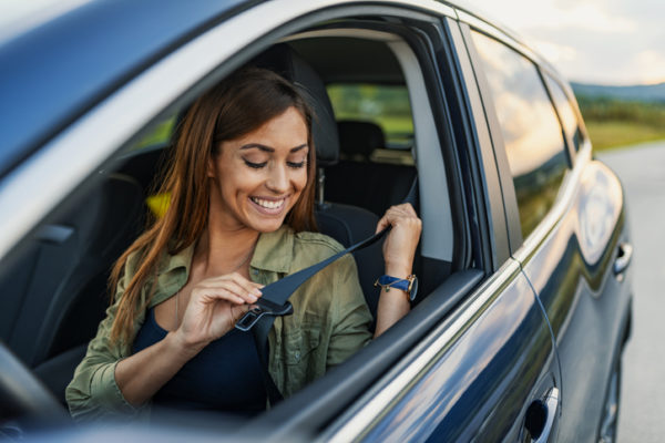 Female driver smiles while buckling her seatbelt