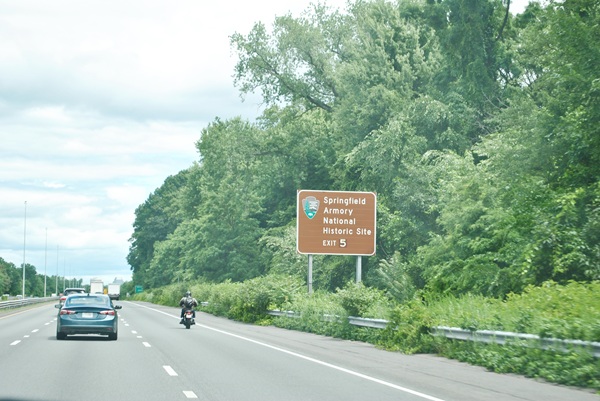 Motorcycle and cars traveling on I-91 North near a sign for Springfield Armory National Historic Site at Exit 5.